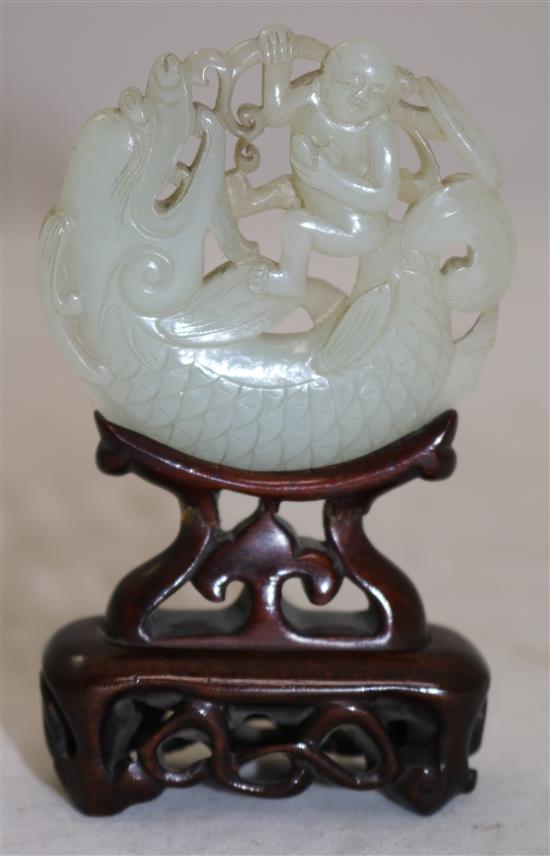 A Chinese pale celadon jade fish-dragon and boy disc, 18th century, diameter 6.1cm, rosewood stand